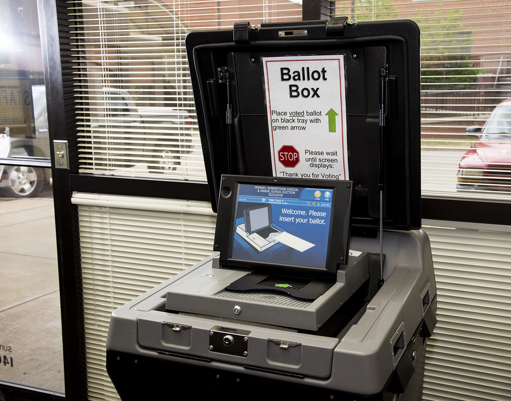 Voters insert their printed ballots into an automated ballot box that scans and tallies the votes and deposits the printed ballots into a locked container. Division of Agriculture photo by Fred Miller